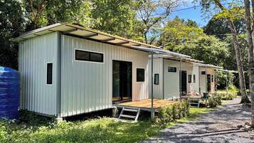 Een rij vakantiehuisjes met houten terrassen, omgeven door groen en bomen.