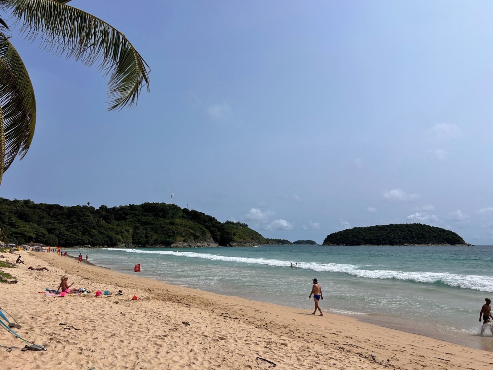 A beach with clear skies, calm waters, and a few people.
