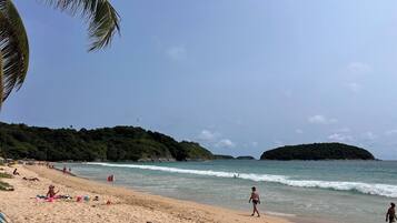 A beach with clear skies, calm waters, and a few people.