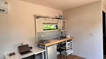 Eine kompakte Küchenzeile mit integriertem Mikrowellenherd, einem kleinen Kühlschrank und einer Holzausziehtafel.