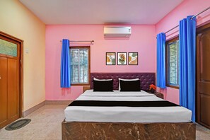 Una camera da letto con un letto, una finestra con tende, un condizionatore d'aria a muro e tre quadri incorniciati.