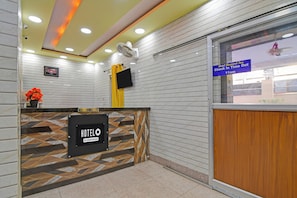 A hotel reception area with a reception desk, a digital screen, and a sign indicating check-in time.