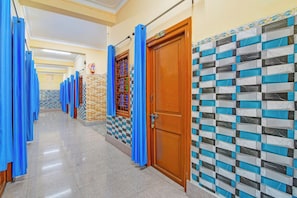 A hotel corridor with blue curtains, a fire extinguisher, a checkered wall, and a wooden door.