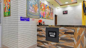 A hotel reception area with marble walls, a check-in sign, and a digital clock.