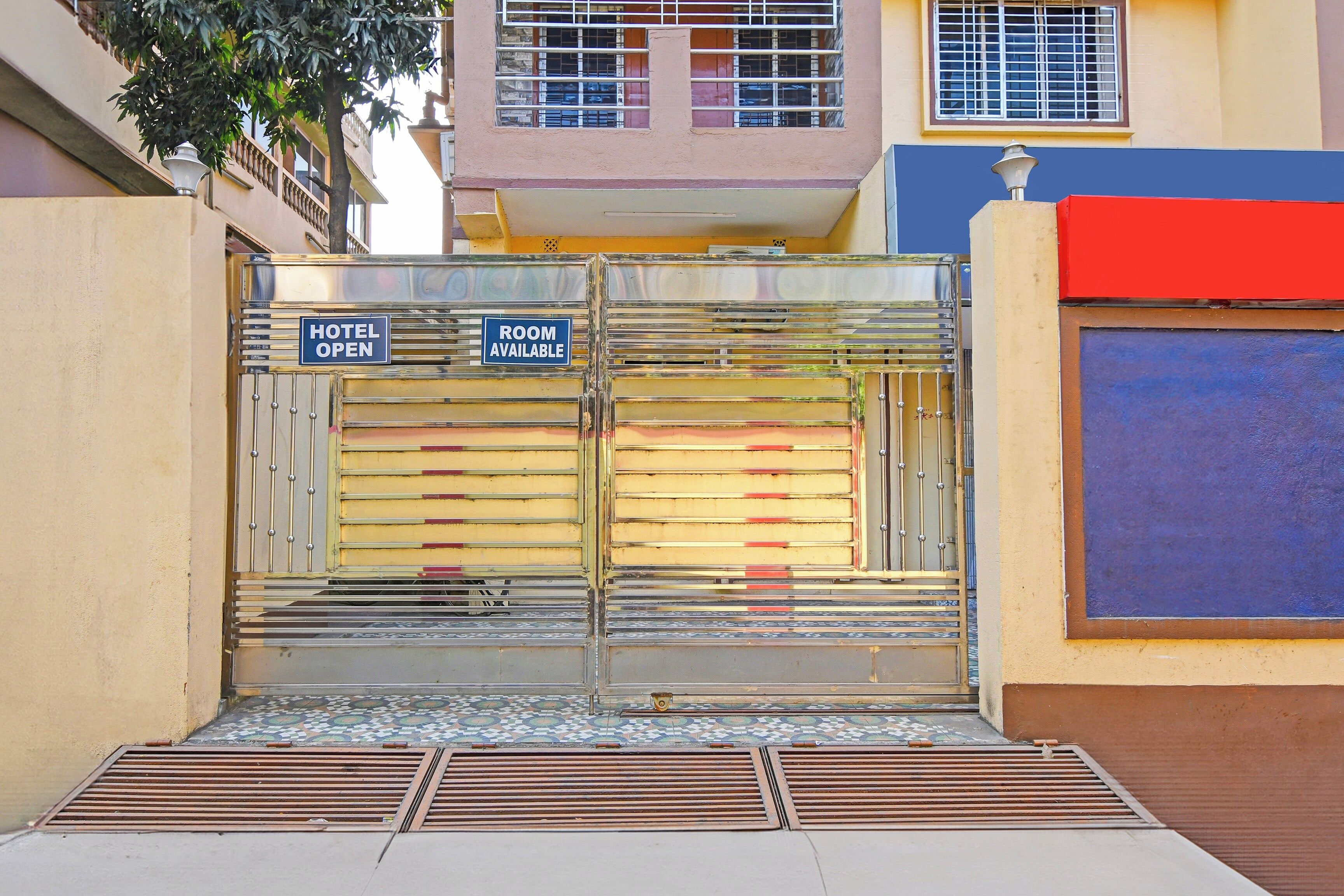 A hotel entrance with a metal gate, a tiled floor, and a visible staircase leading up.