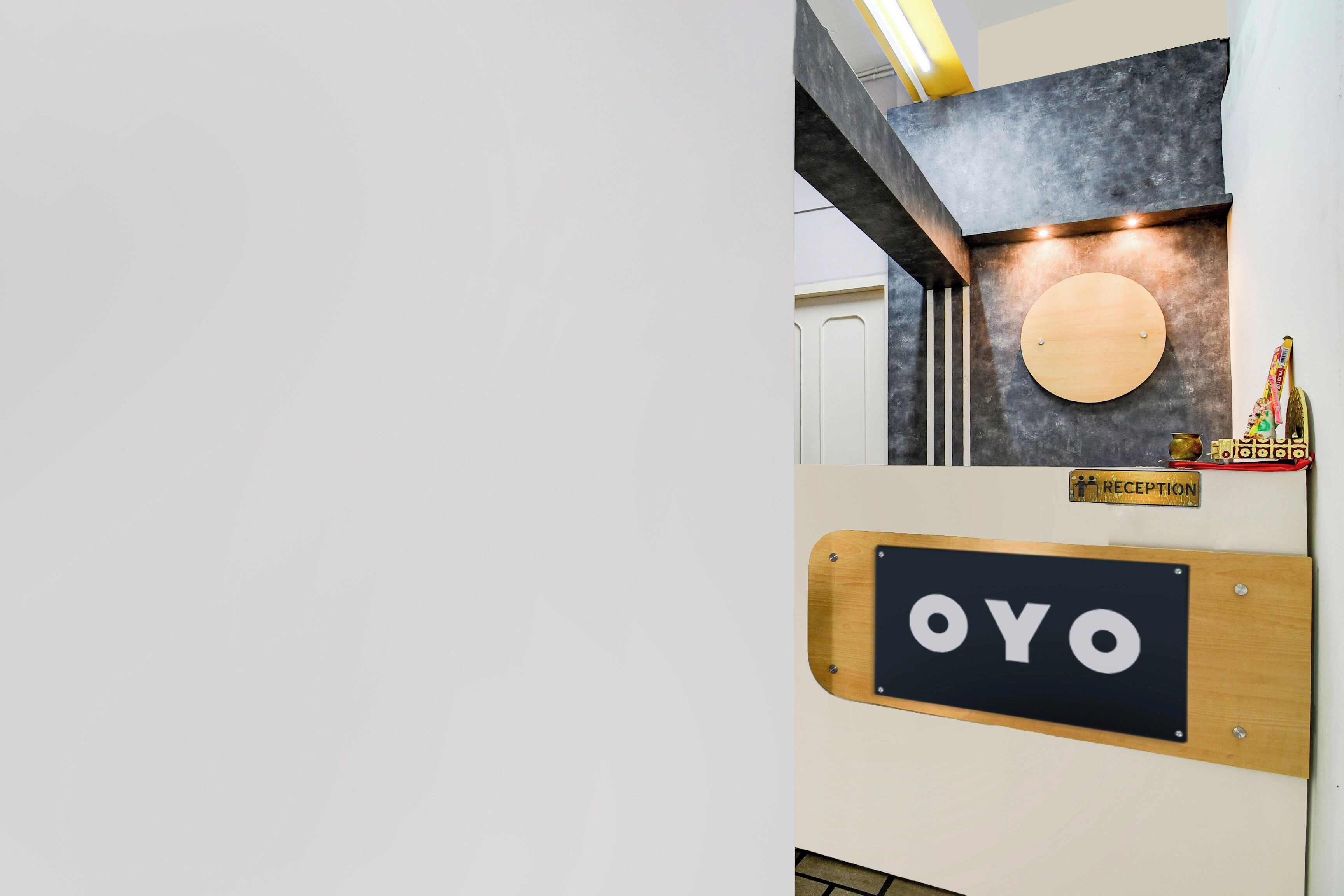 A reception area with a wooden reception desk labeled 'OYO,' a reception sign, and a wall-mounted circular object.