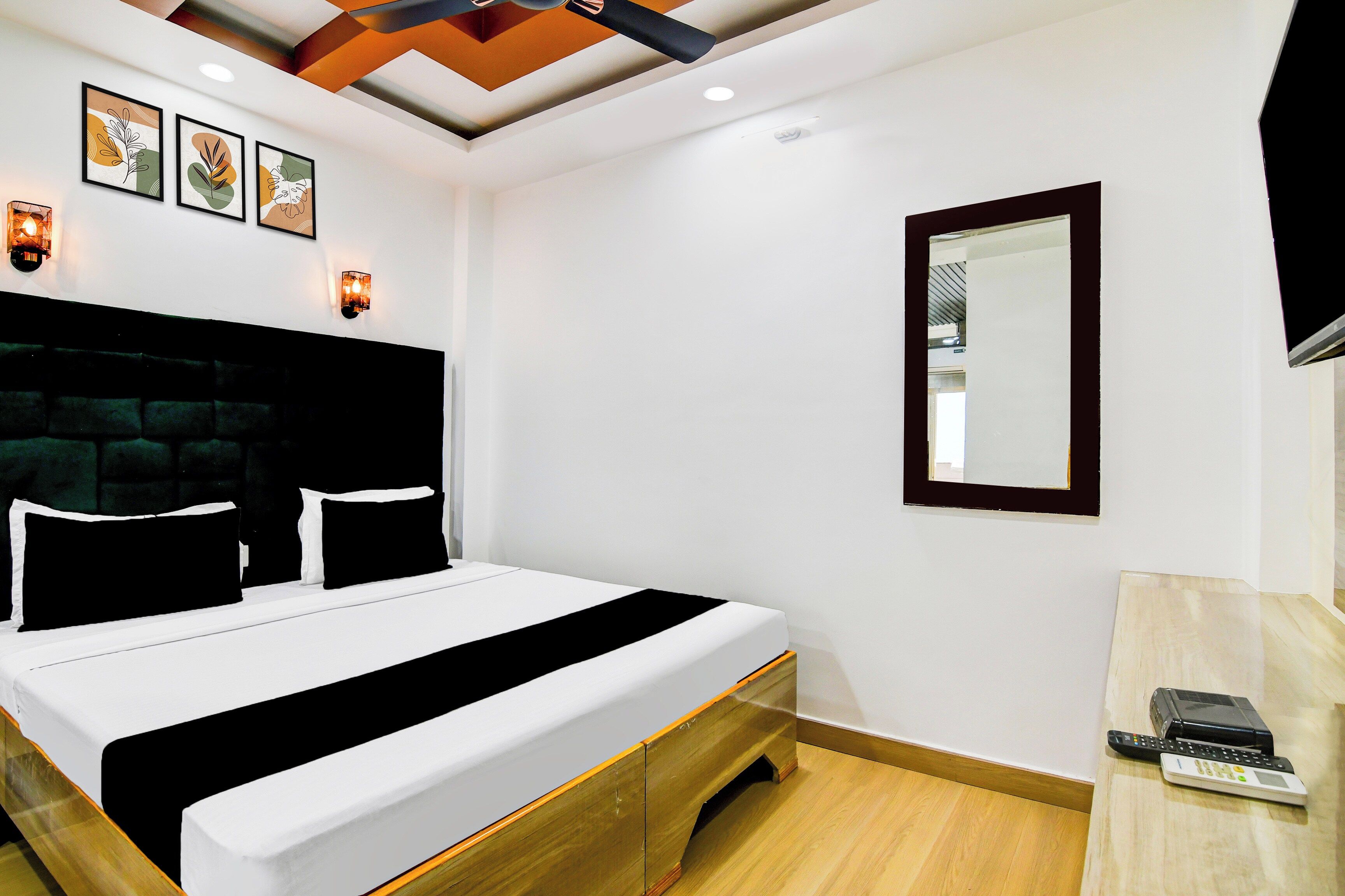 Habitación de hotel con cama, mesita de noche, espejo e iluminación empotrada en el techo.