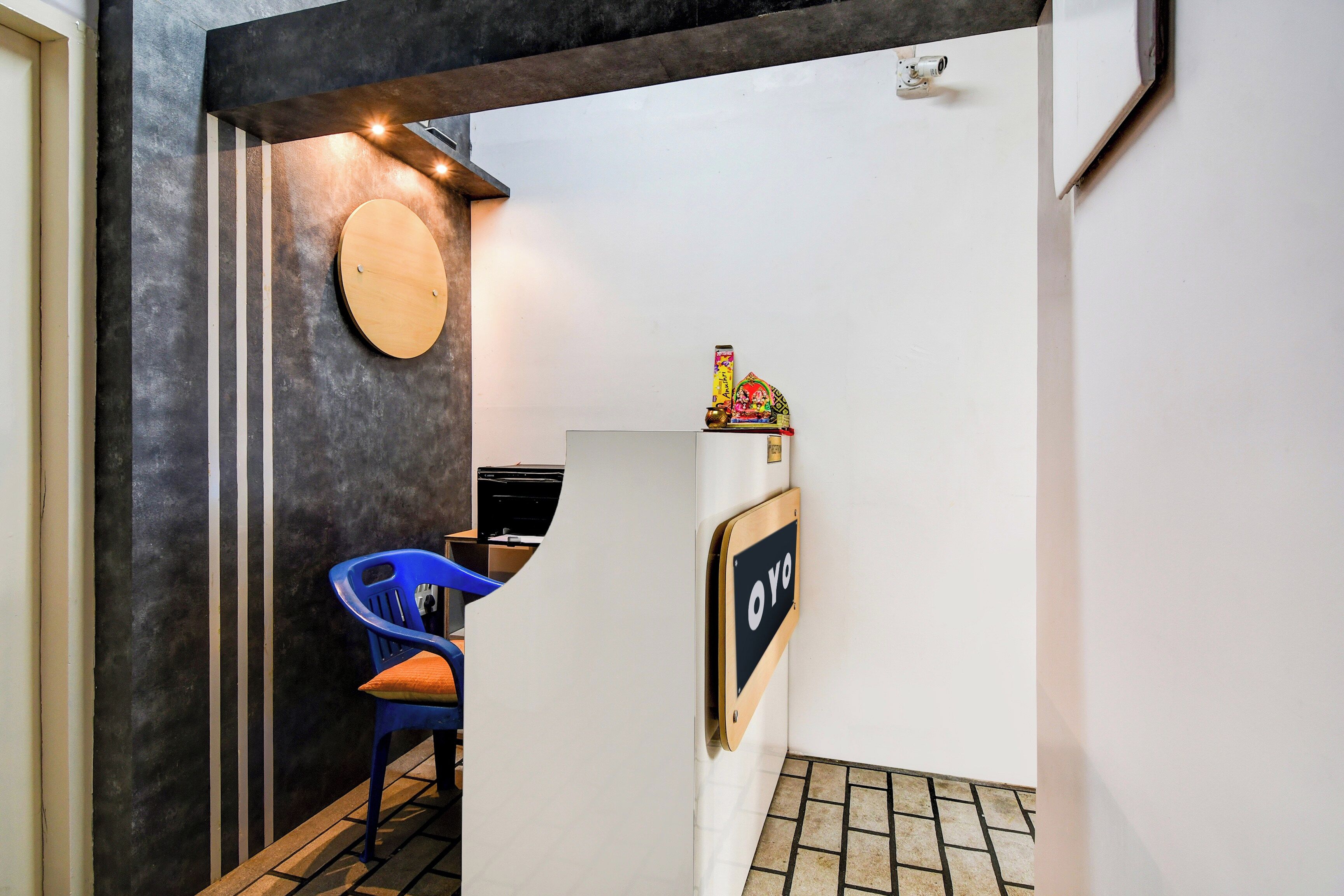 Zona de recepción con un mostrador, una silla azul, un letrero en la pared y un adorno en la parte superior.