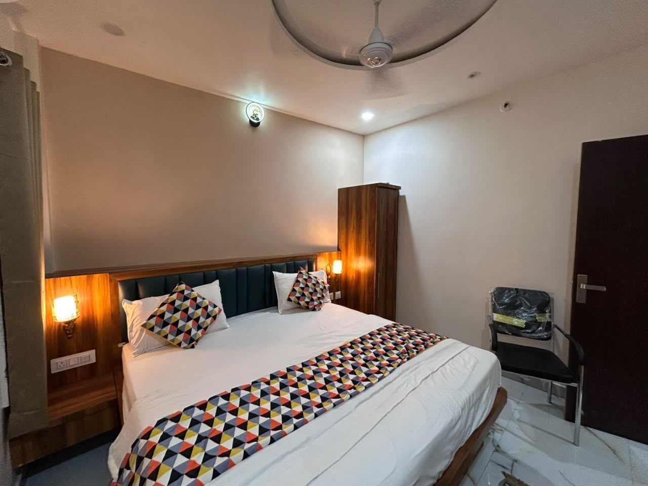 Habitación de hotel con cama, una silla, armario y ventilador de techo.