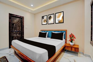 Un dormitorio con una cama, una mesita de noche, un florero con flores y tres cuadros en la pared.