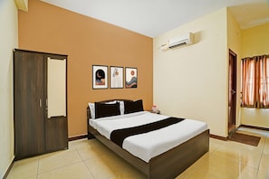 Ein Hotelzimmer mit einem Bett, einem Kleiderschrank, einer Tür und einer Klimaanlage.