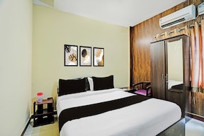 Ein Hotelzimmer mit einem Bett, einem Kleiderschrank, einer Klimaanlage und Wandbildern.