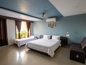 A hotel room with a large bed, a smaller bed, a sofa, a ceiling fan, and an air conditioning unit. - Collection O Srikakulam (Laveru)