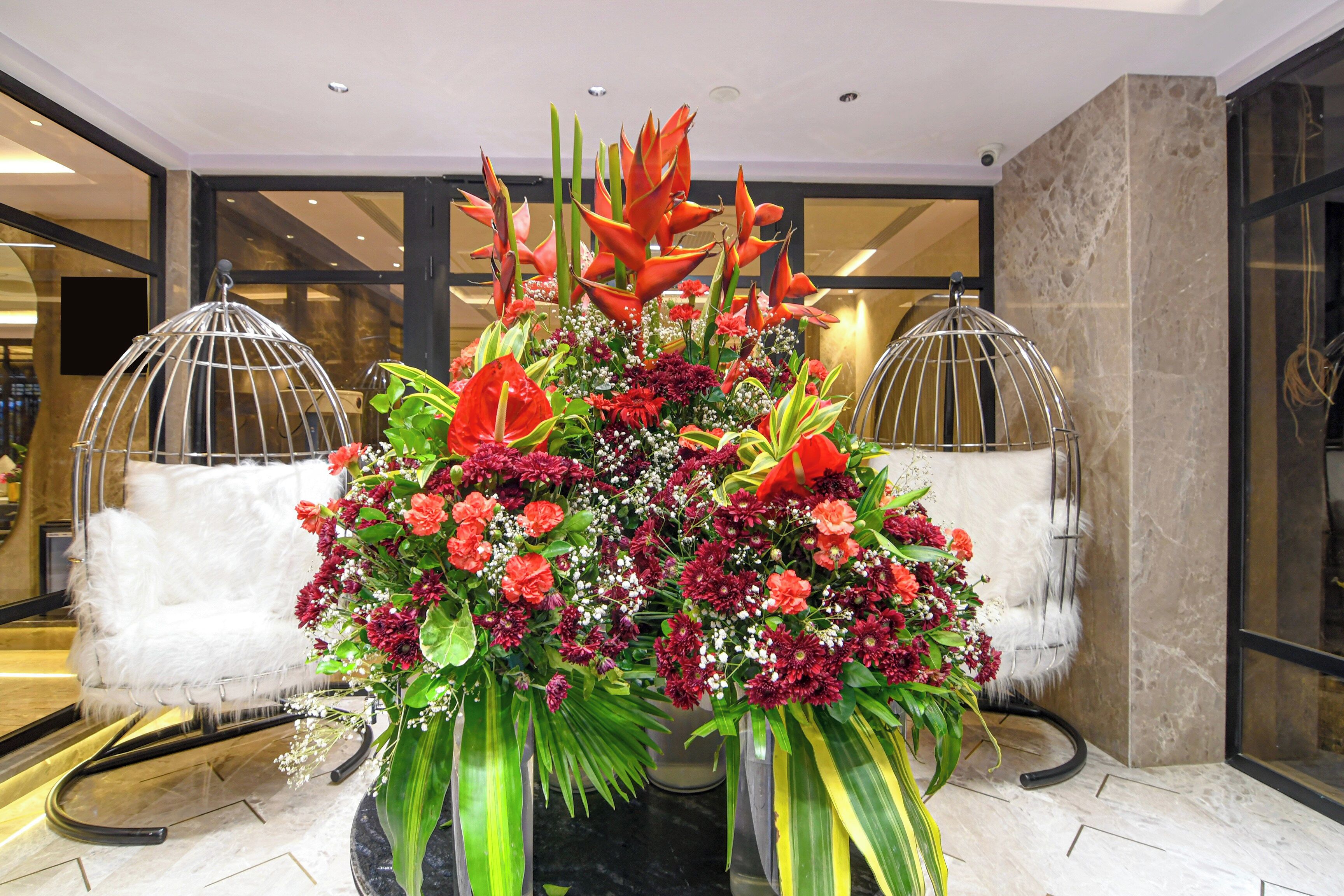 Une composition florale dans un hall d’entrée, avec un sol en marbre et une cloison en verre.