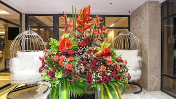 Une composition florale dans un hall d’entrée, avec un sol en marbre et une cloison en verre.