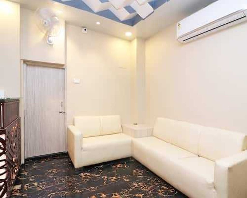 A room with a white sofa, a small side table, a ceiling fan, and an air conditioning unit.