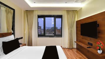 A hotel room with a bed, a TV, a wooden headboard, a window with curtains, and a ceiling fan.