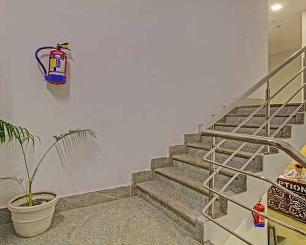 Una escalera con barandillas de metal, una planta en maceta y un extintor de incendios fijado a la pared.