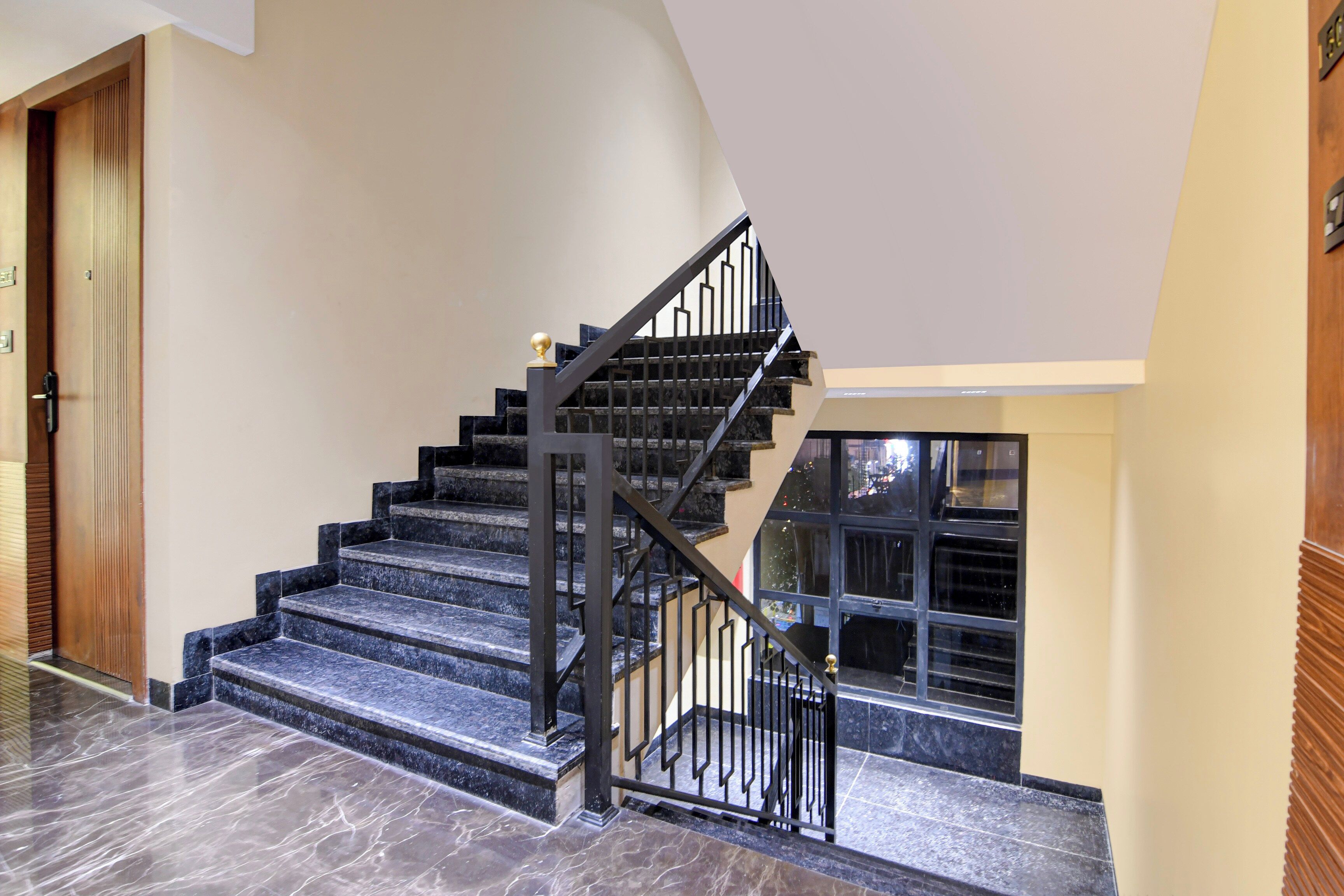 A staircase with black railings and marble steps, leading to an upper floor.