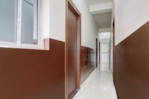 A corridor with a door on the left, a window on the right, and a door at the end.