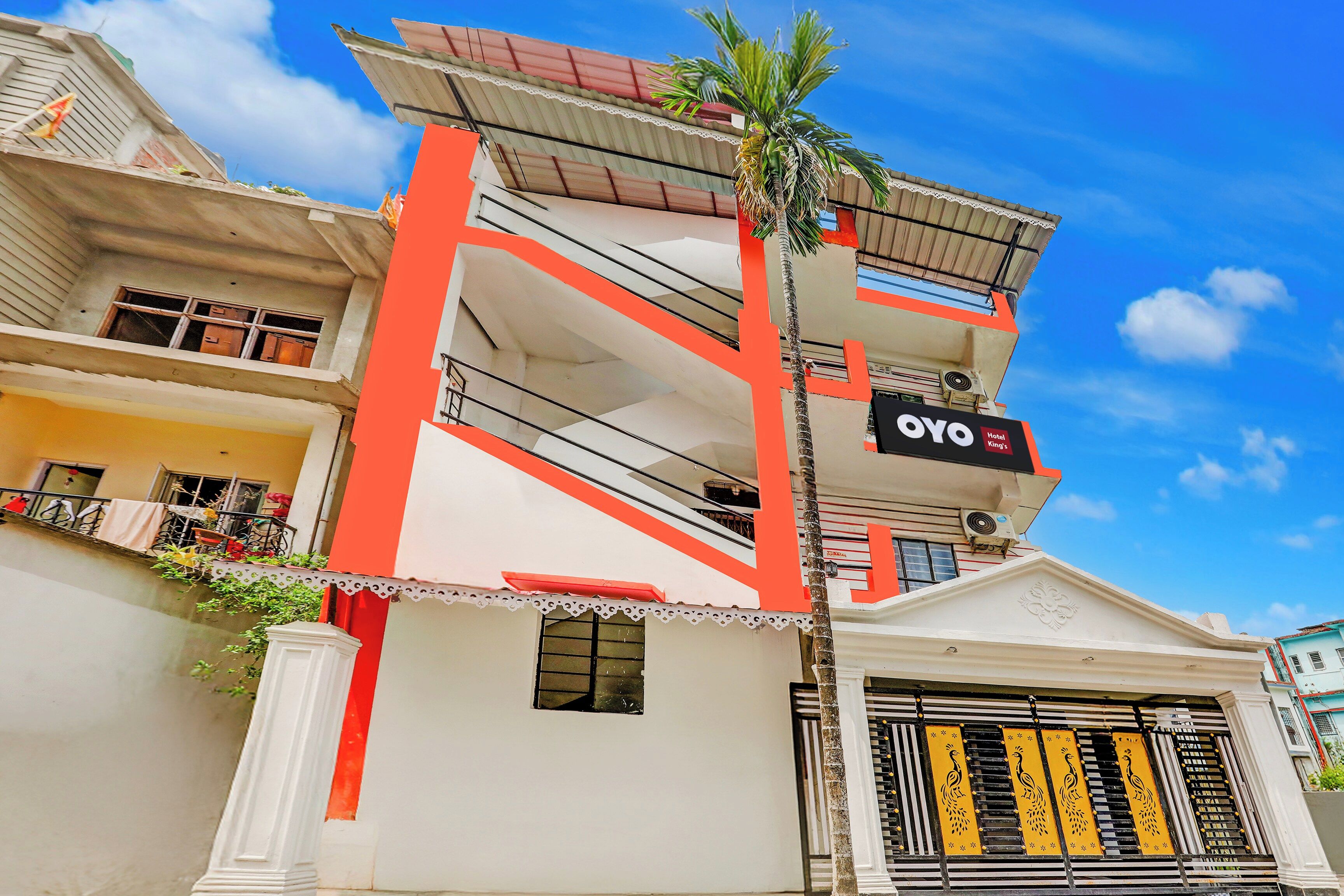 A hotel with a prominent red and white facade, balconies, and a sign for 'OYO Hotel King's'.