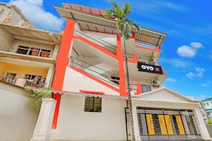 Un hotel con una fachada destacada de color rojo y blanco, balcones y un letrero que dice 'OYO Hotel King's'.