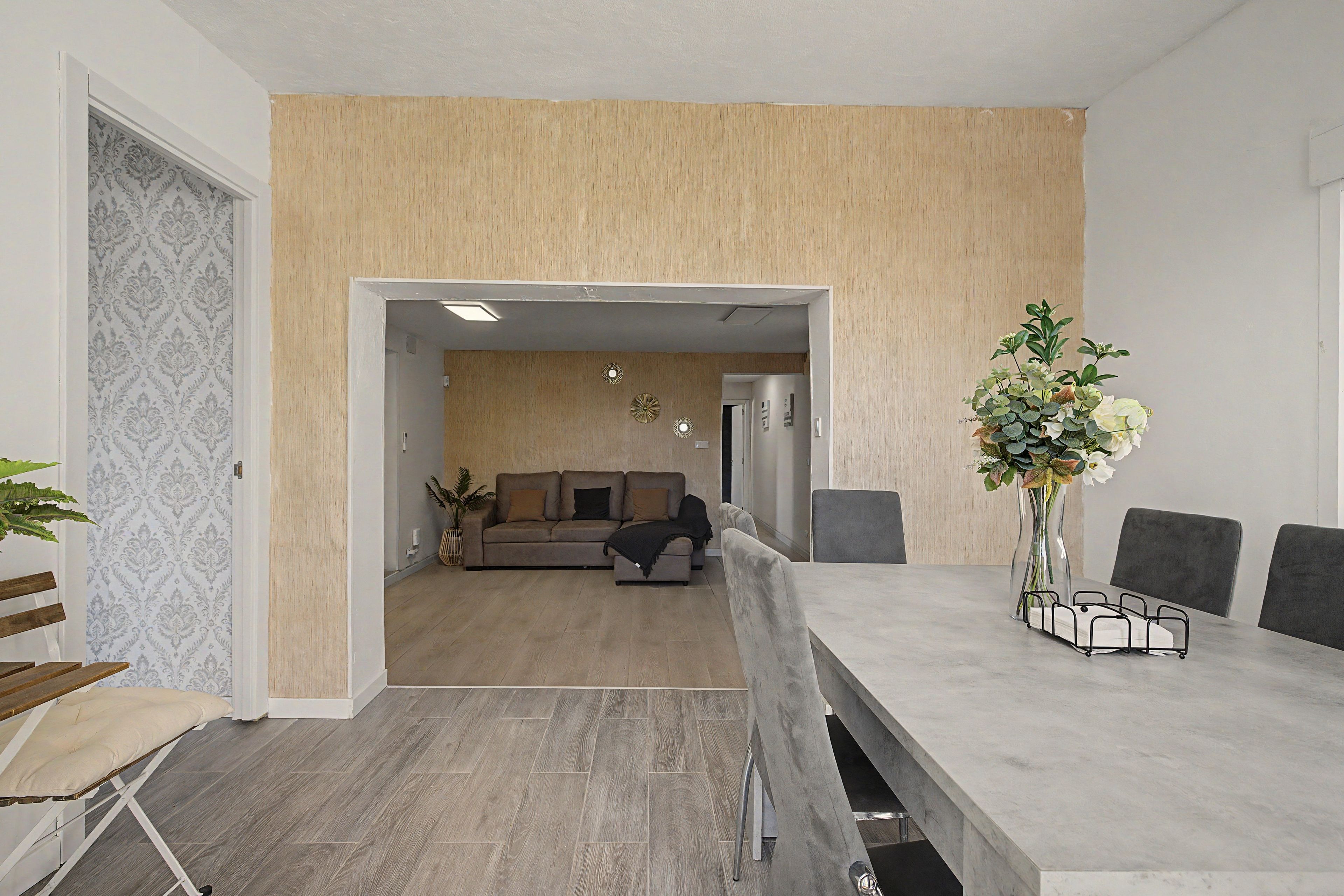 Een moderne woonkamer met een bank, een eettafel met stoelen en een decoratieve plant.