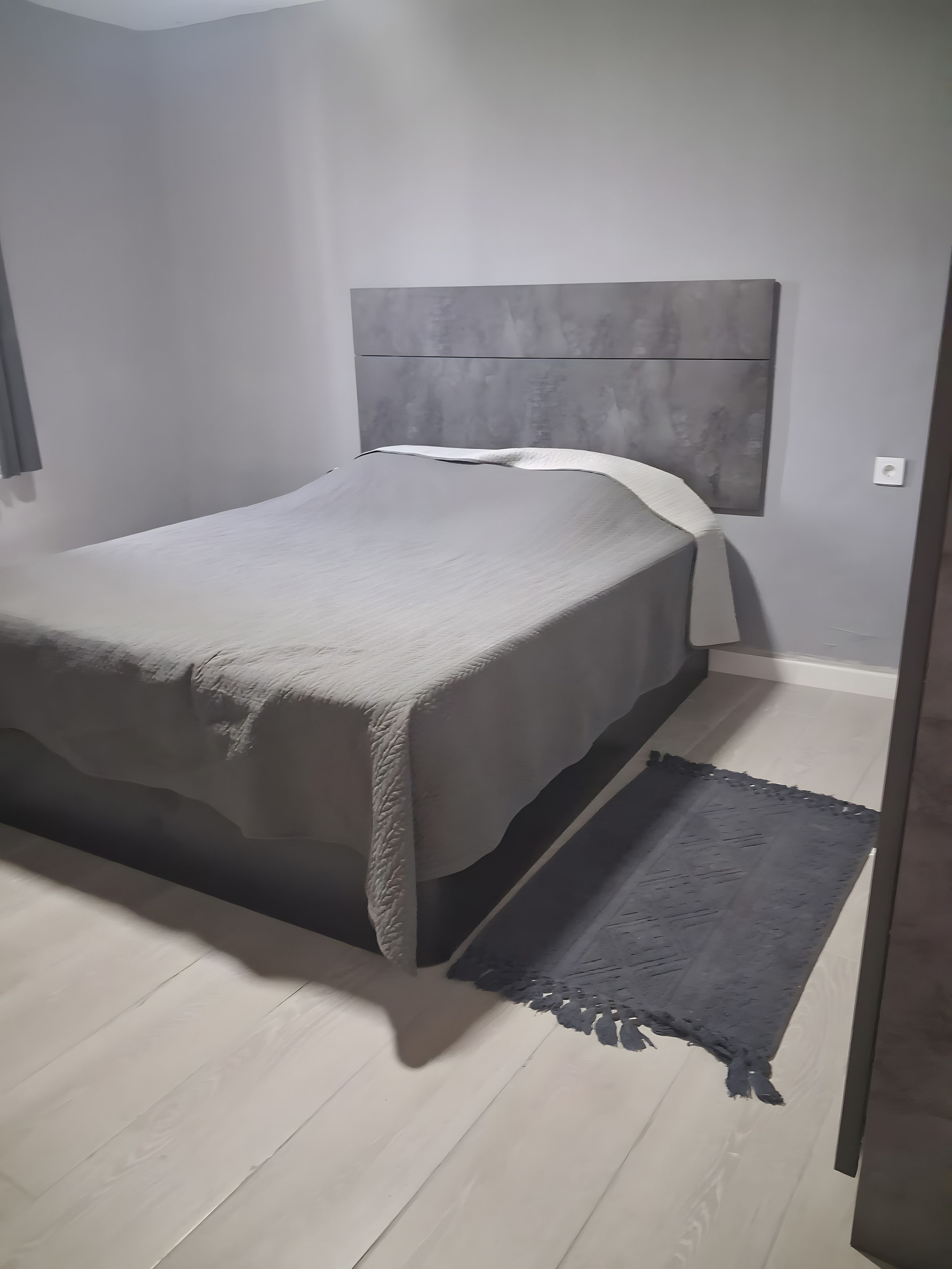 A bedroom with a bed, a headboard, a bedside table, and a rug.