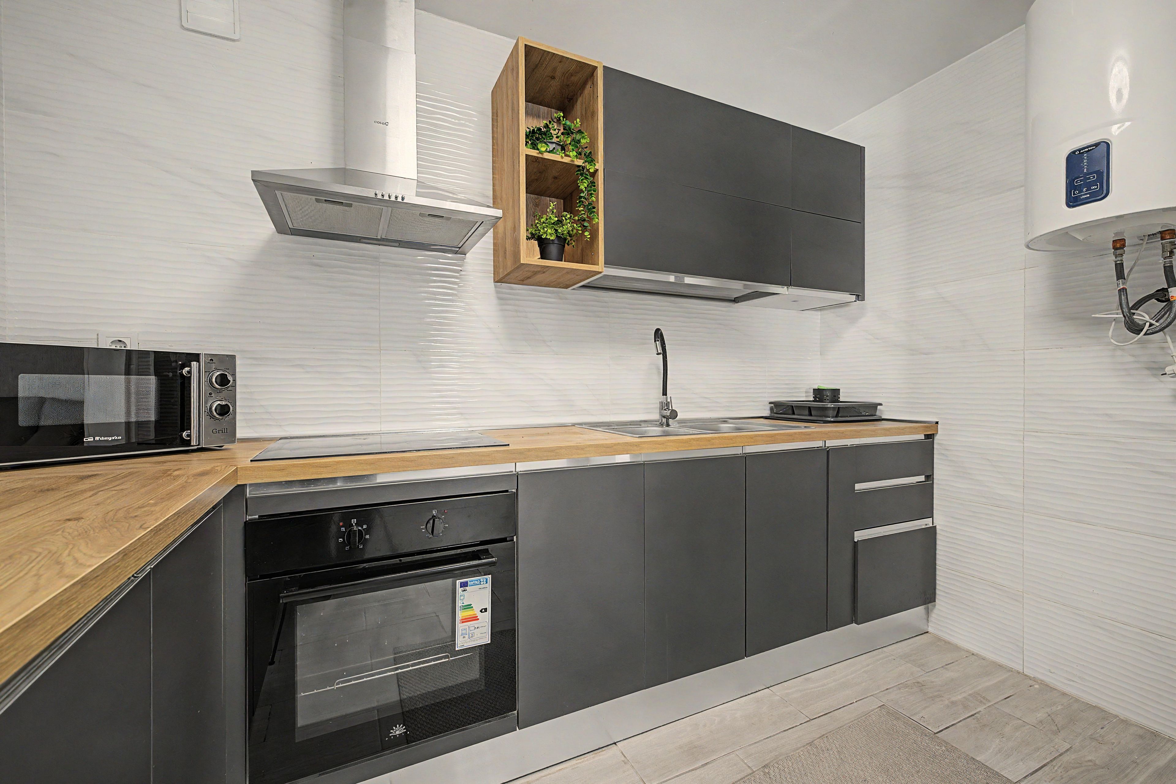Een moderne keuken met een ingebouwde oven, magnetron en een houten aanrecht.