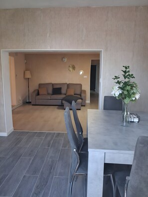 A modern living room with a sofa, a dining table, and a vase with flowers.