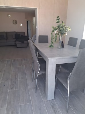 A dining area with a rectangular table, grey chairs, and a vase with flowers.