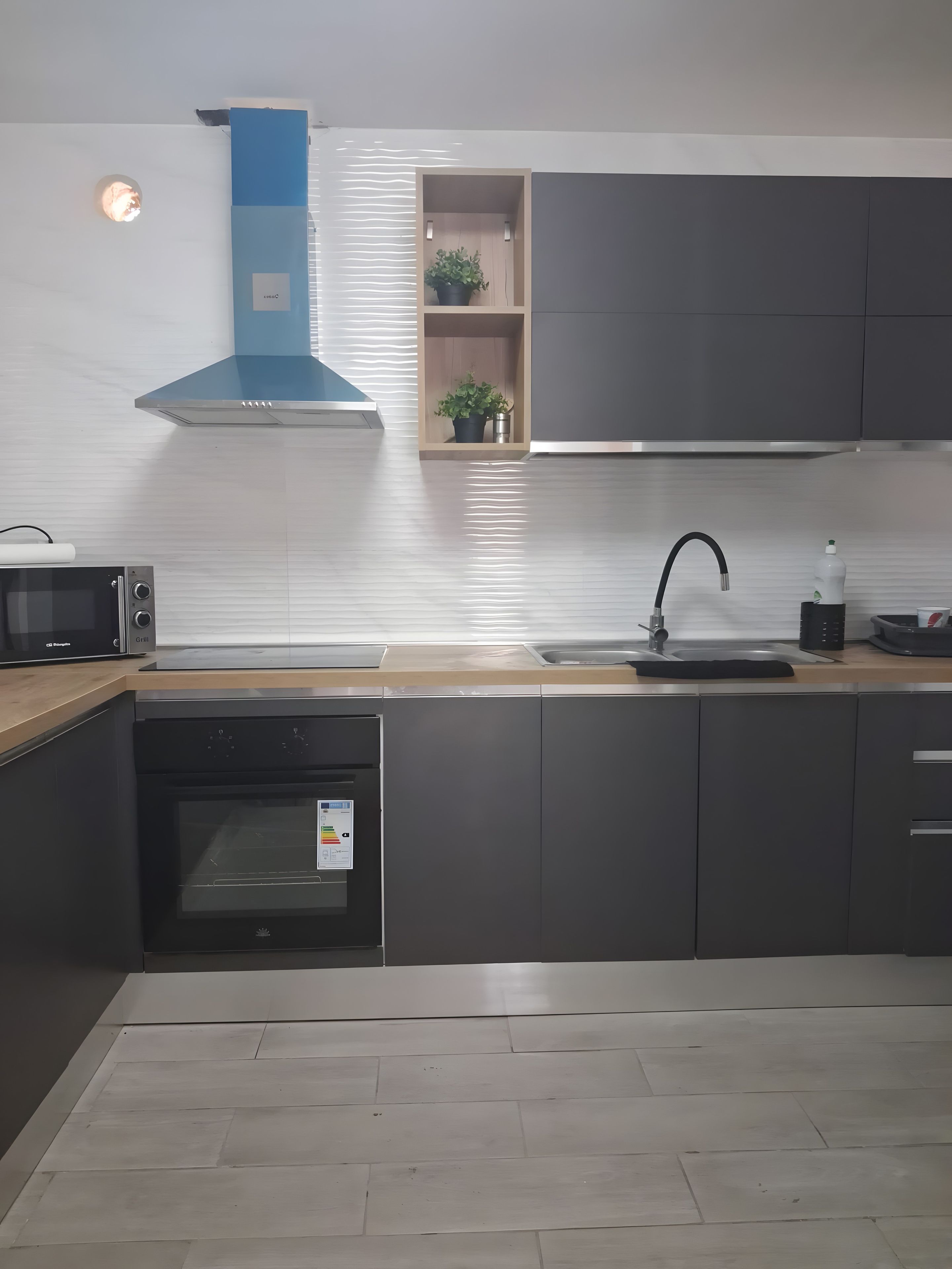 Una cocina moderna con microondas integrado, horno y campana extractora de acero inoxidable.