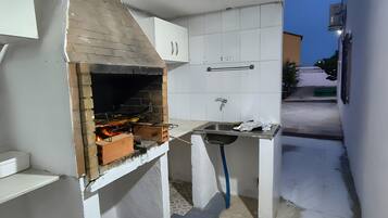 Une cuisine compacte dotée d’un barbecue intégré, d’un évier et d’un petit plan de travail.