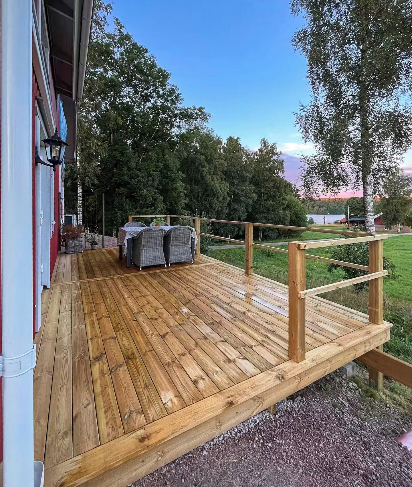 A wooden deck with outdoor seating and a view of a lake.