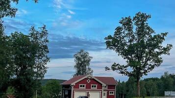A red barn with a white garage door, surrounded by lush green fields and trees.