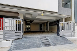 Uma entrada com portão e um caminho de azulejos que leva à entrada de um edifício.