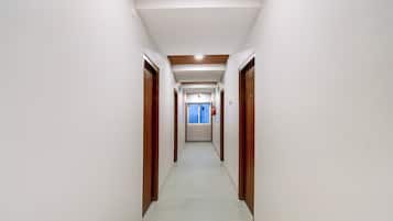 Un couloir avec des portes de part et d’autre, un sol carrelé et un extincteur fixé au mur.