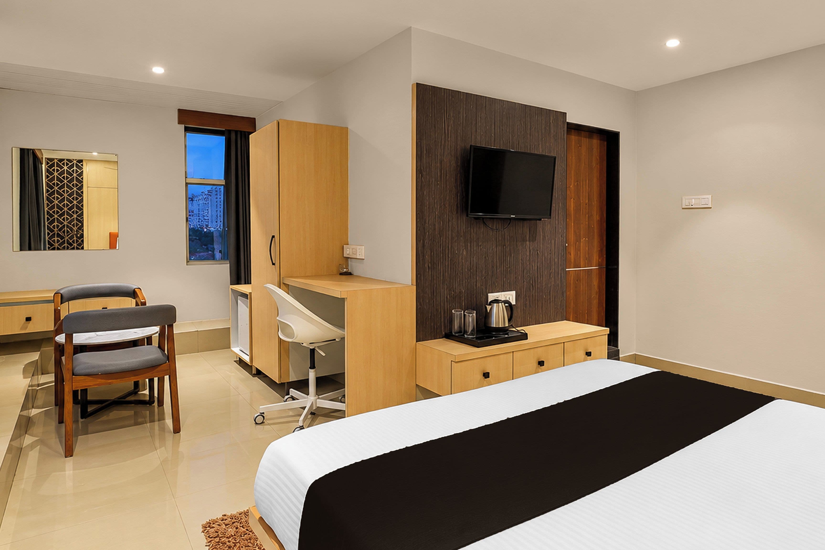 A hotel room with a bed, desk, chair, TV, and a window with a view.