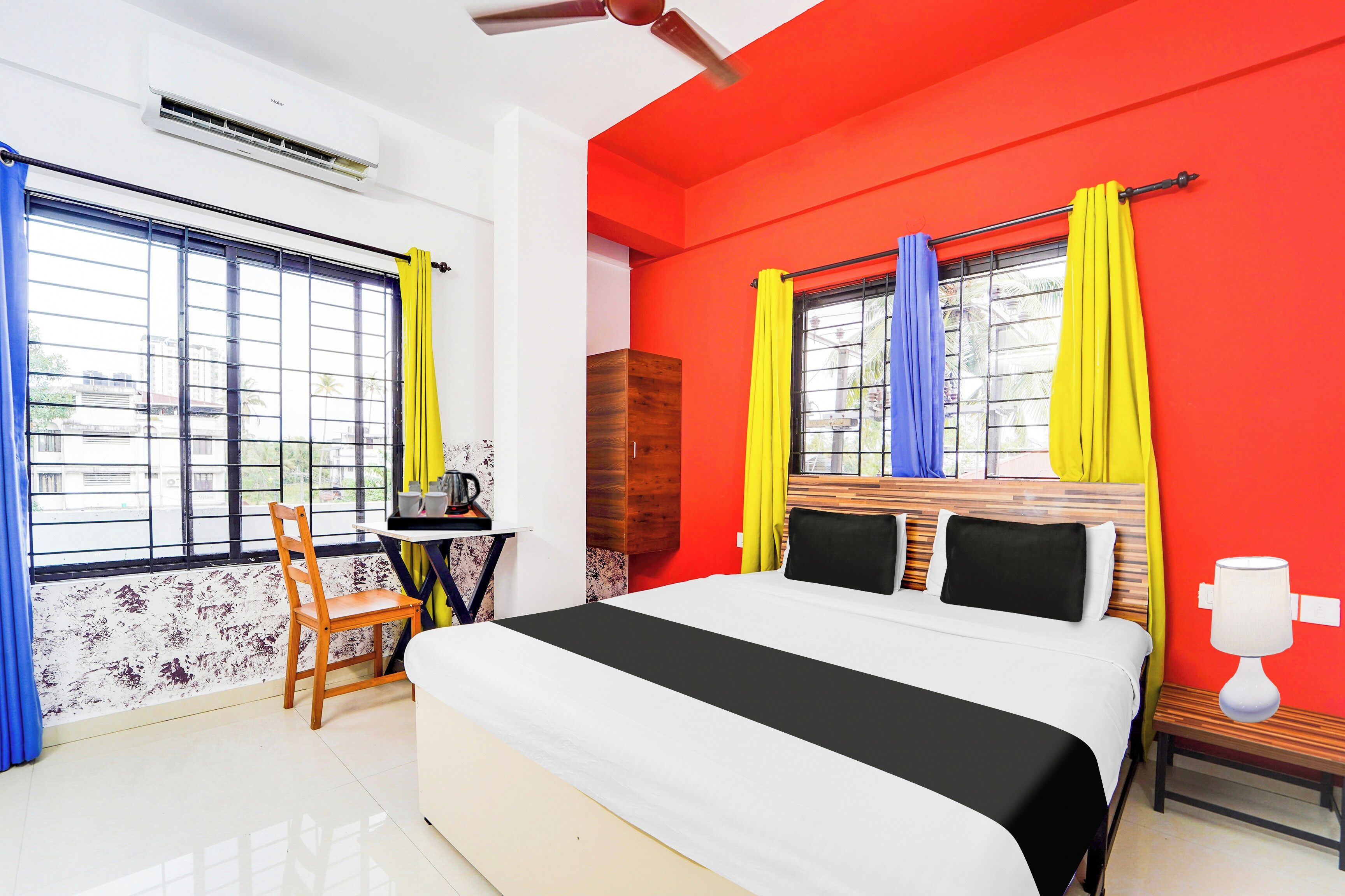 Una habitación con cama, escritorio y silla. Hay ventanas con cortinas.