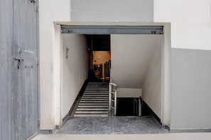 A narrow stairway leading to a landing with a door on the left and a staircase on the right.