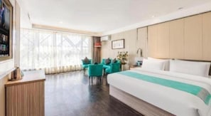 Una habitación de hotel con una cama grande, un escritorio y un área de descanso con sillas.