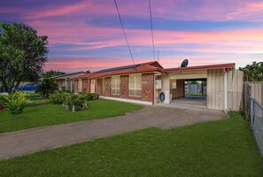 A single-story house with a garage, a satellite dish, and a well-maintained lawn. - entire 3BR Home | 3 Queen Beds, Garage & Fenced (Crestmead)