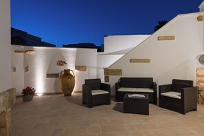 An outdoor seating area with wicker furniture, a large vase, and a potted plant. - New Listing (Alliste)