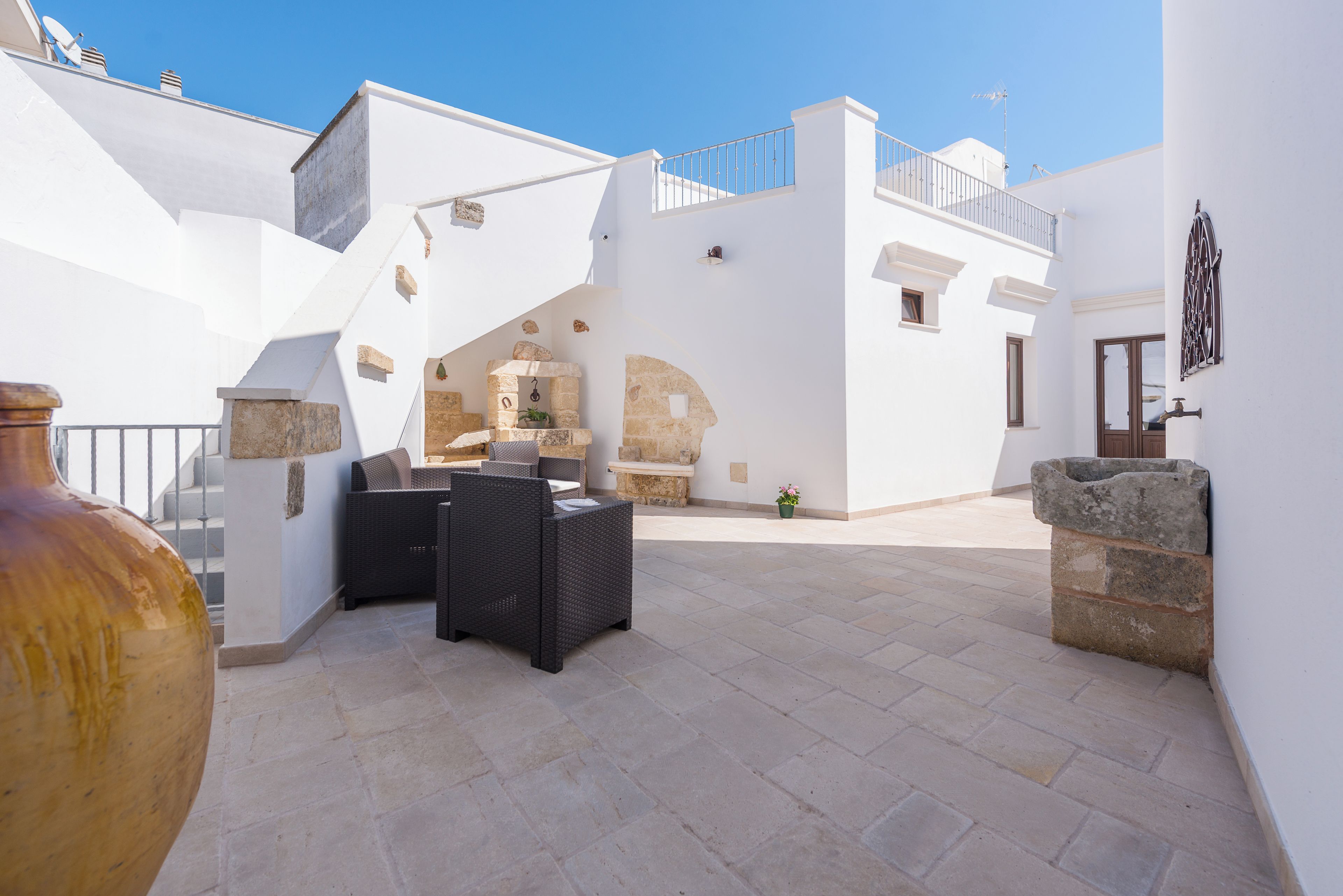 A courtyard with stone flooring, outdoor furniture, and a stone wall.