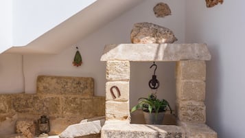 A stone bench with a lantern, a stone wall, and a hanging plant.
