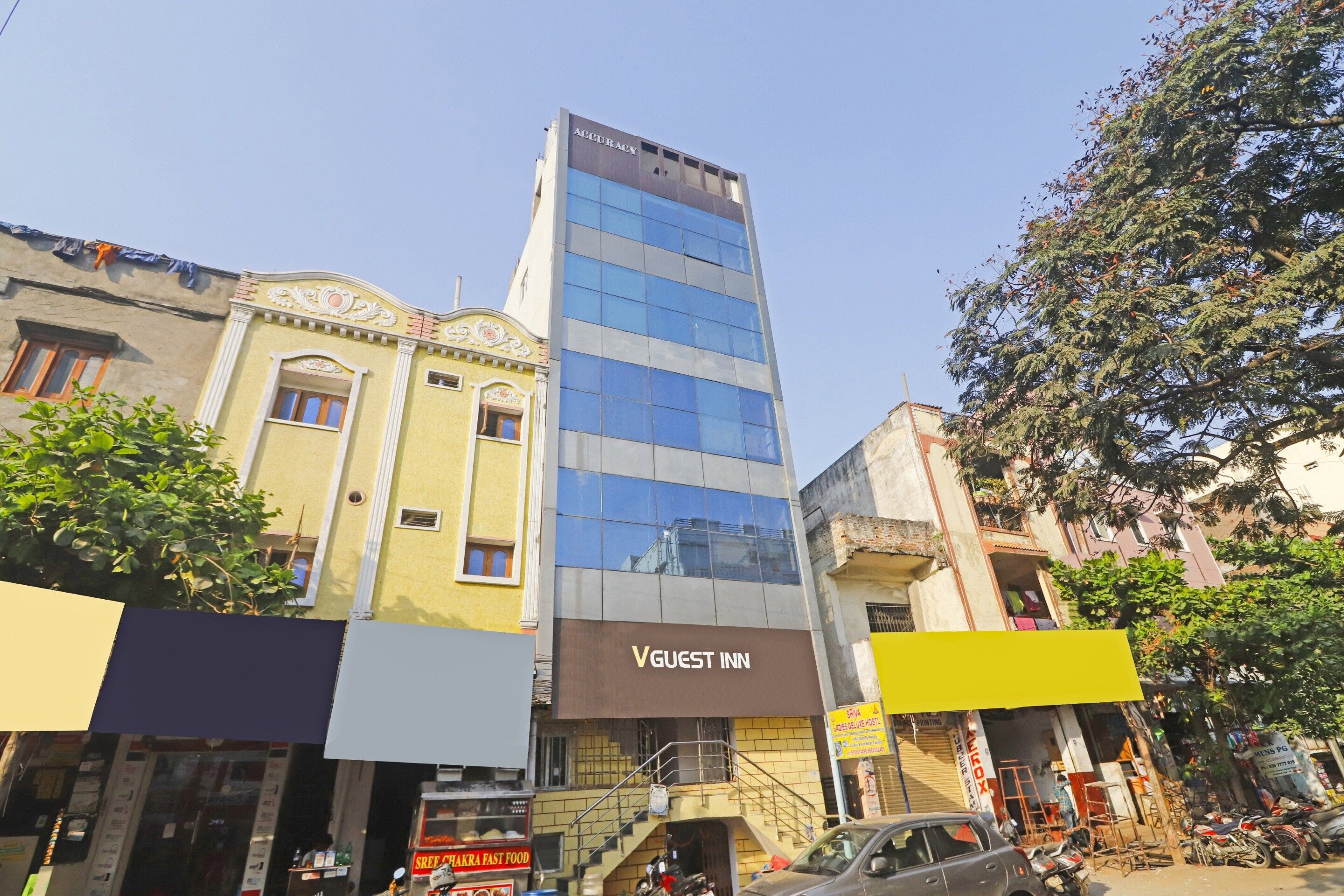 Un edificio de varios pisos con un letrero que indica 'VGUEST INN', señal de alojamiento para huéspedes.