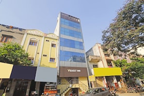 Un edificio de varios pisos con un letrero que indica 'VGUEST INN', señal de alojamiento para huéspedes.