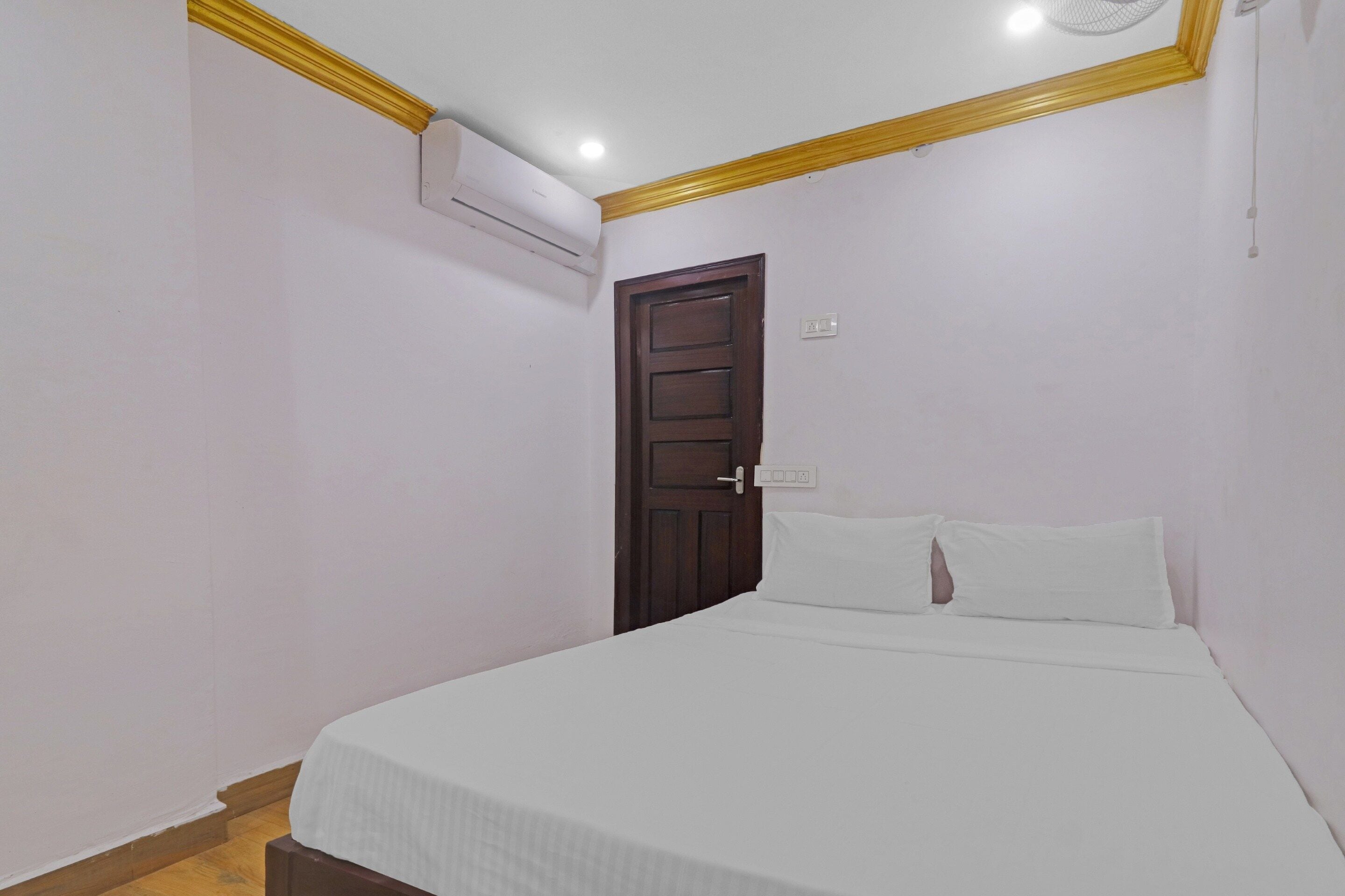 Une chambre avec un lit simple, une porte en bois et un appareil de climatisation fixé au mur.