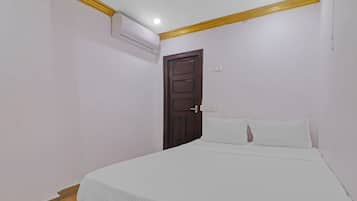 Une chambre avec un lit simple, une porte en bois et un appareil de climatisation fixé au mur.