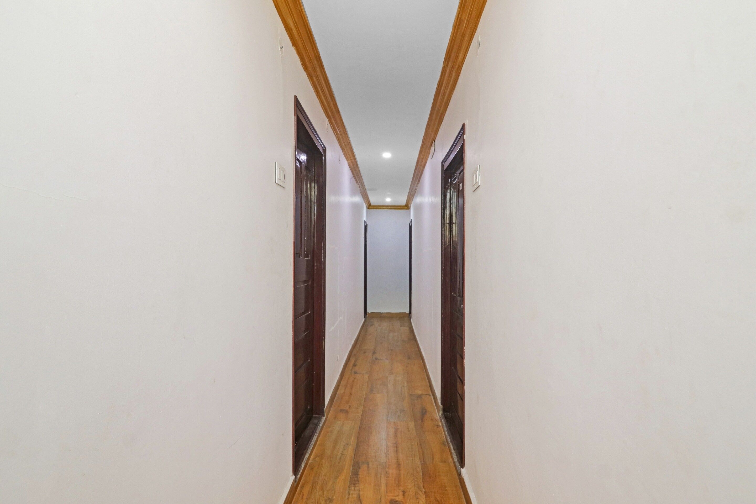 Un pasillo estrecho con suelo de madera y puertas a ambos lados.